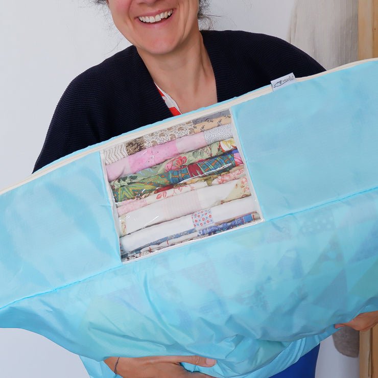 Woman holding a quilt stoage bag with quilts