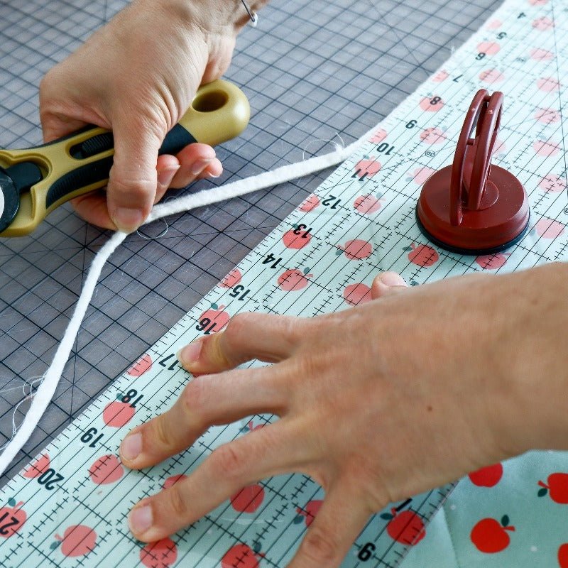 Cutting apple fabric with a Madam Sew rotary cutter and a ruler on a cutting mat