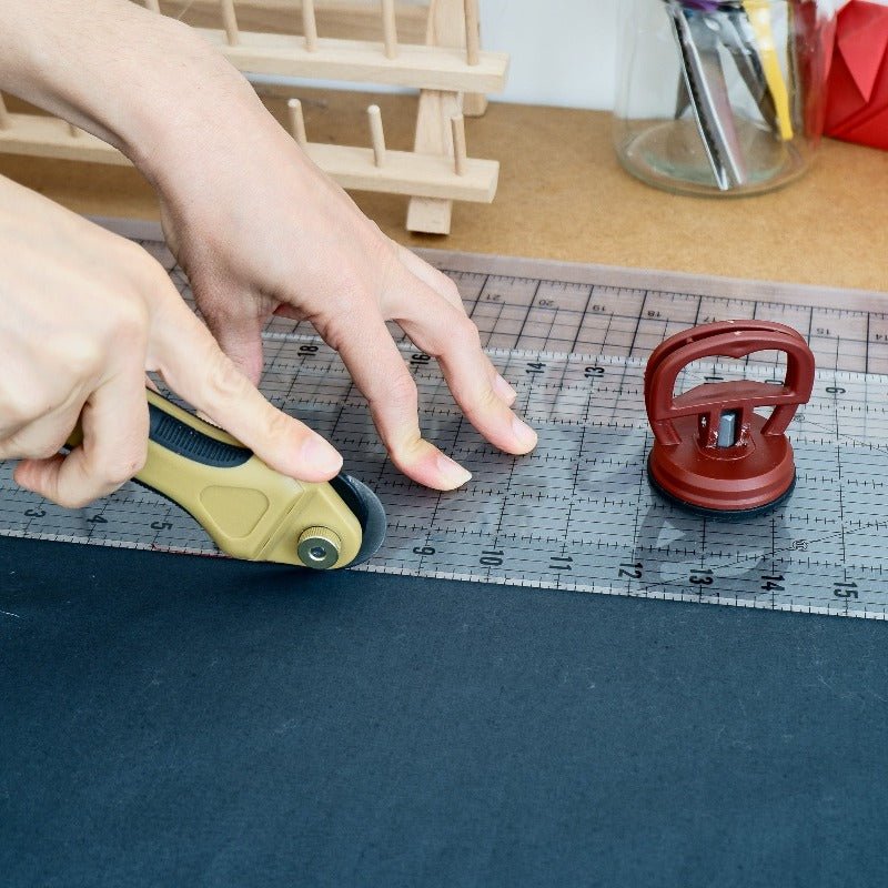 rotary cutter cutting fabric using a ruler with a handle