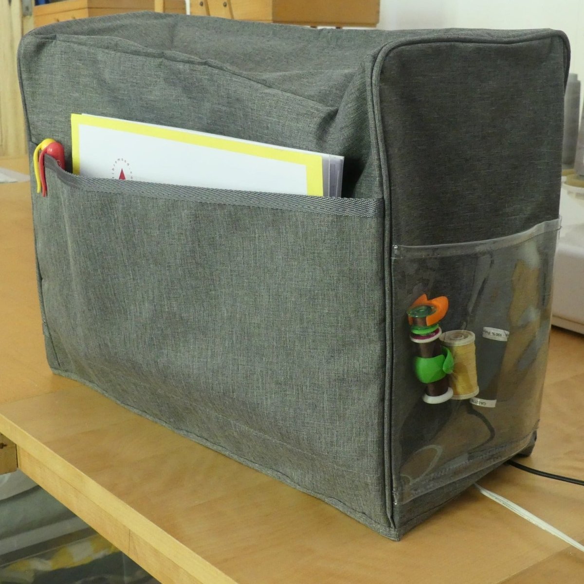 A sewing machine cover that protects a sewing machine from dust with side pockets