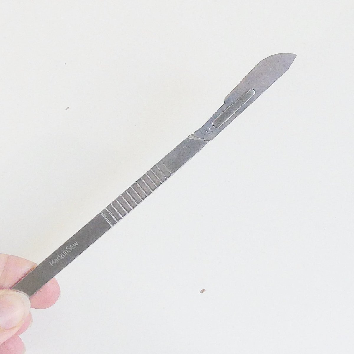 A hand holding the thread knife of the bird nest toolkit with a new blade attached