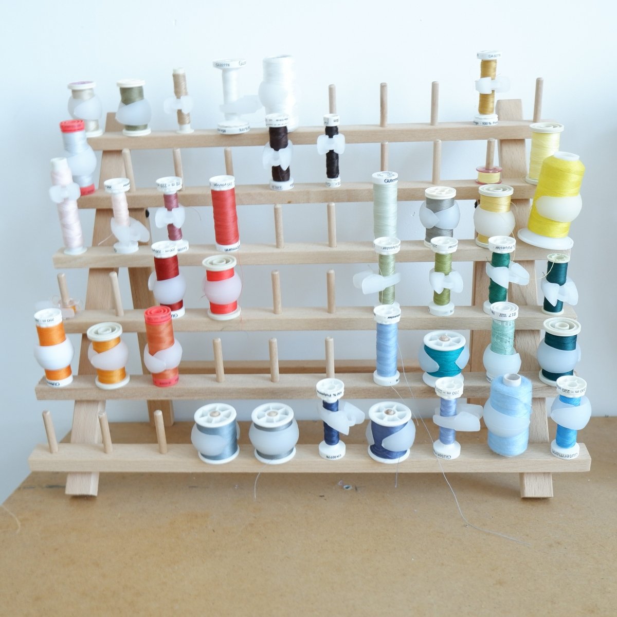 sewing thread rack with spools in different colors and spool huggers and bobbin clamps around the spools