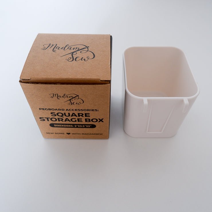 A white box for a peg board to hold pens or other tools with the Madam Sew packaging