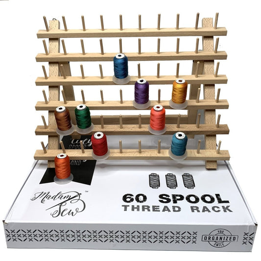 wooden thread rack with some spools in differen colors and a white Madam Sew box