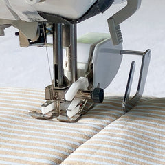 walking foot on a sewing machine sewing on striped fabric, universal fit, with a guide bar sliding in a seam